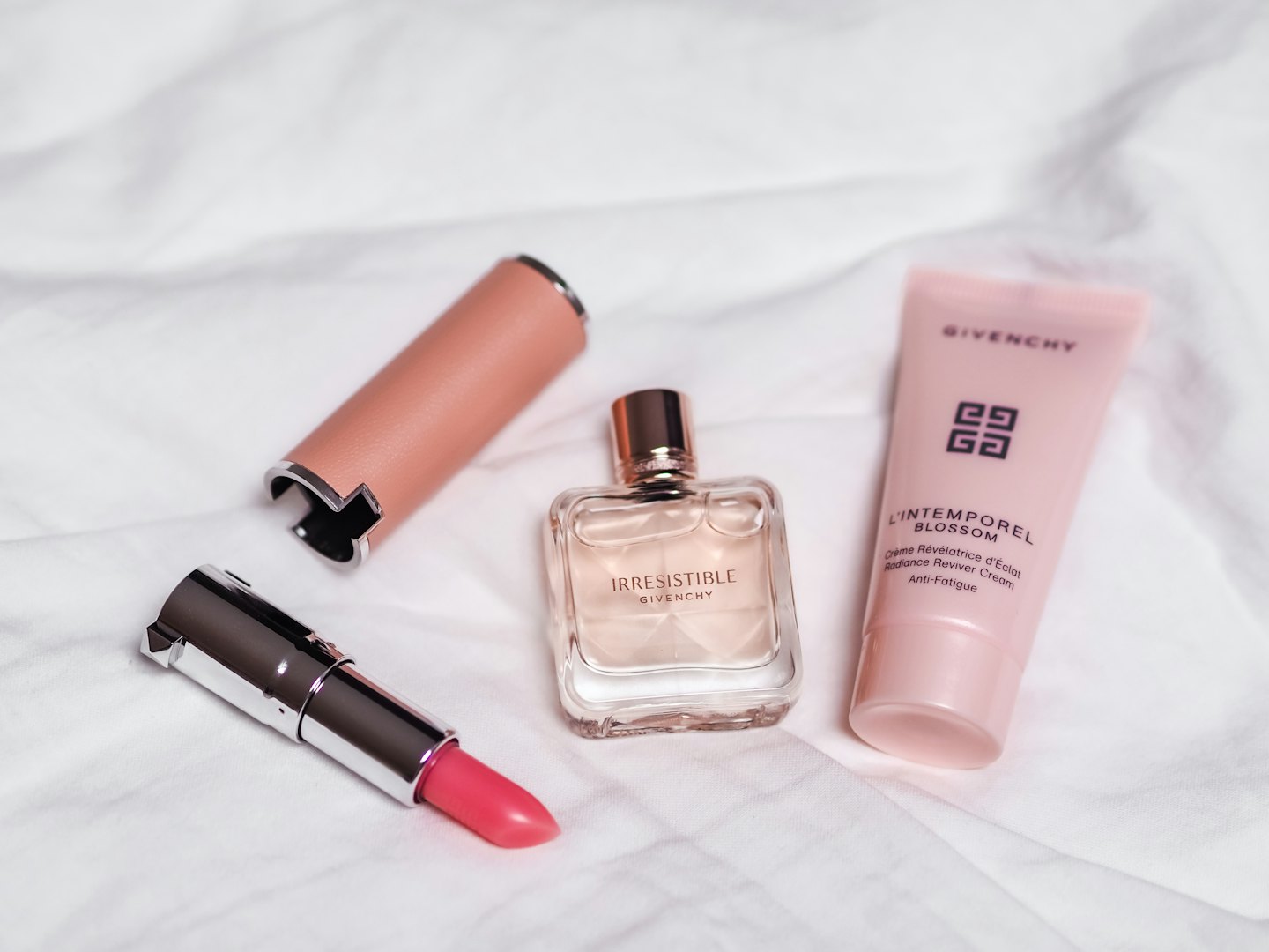 Luxury beauty products arranged on white fabric.