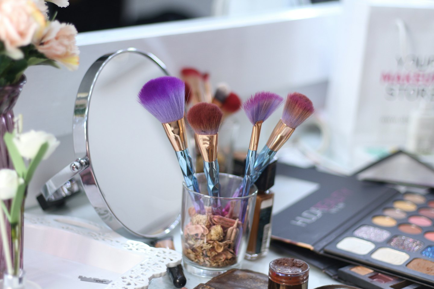 Makeup brushes and cosmetics sit on a white vanity table.